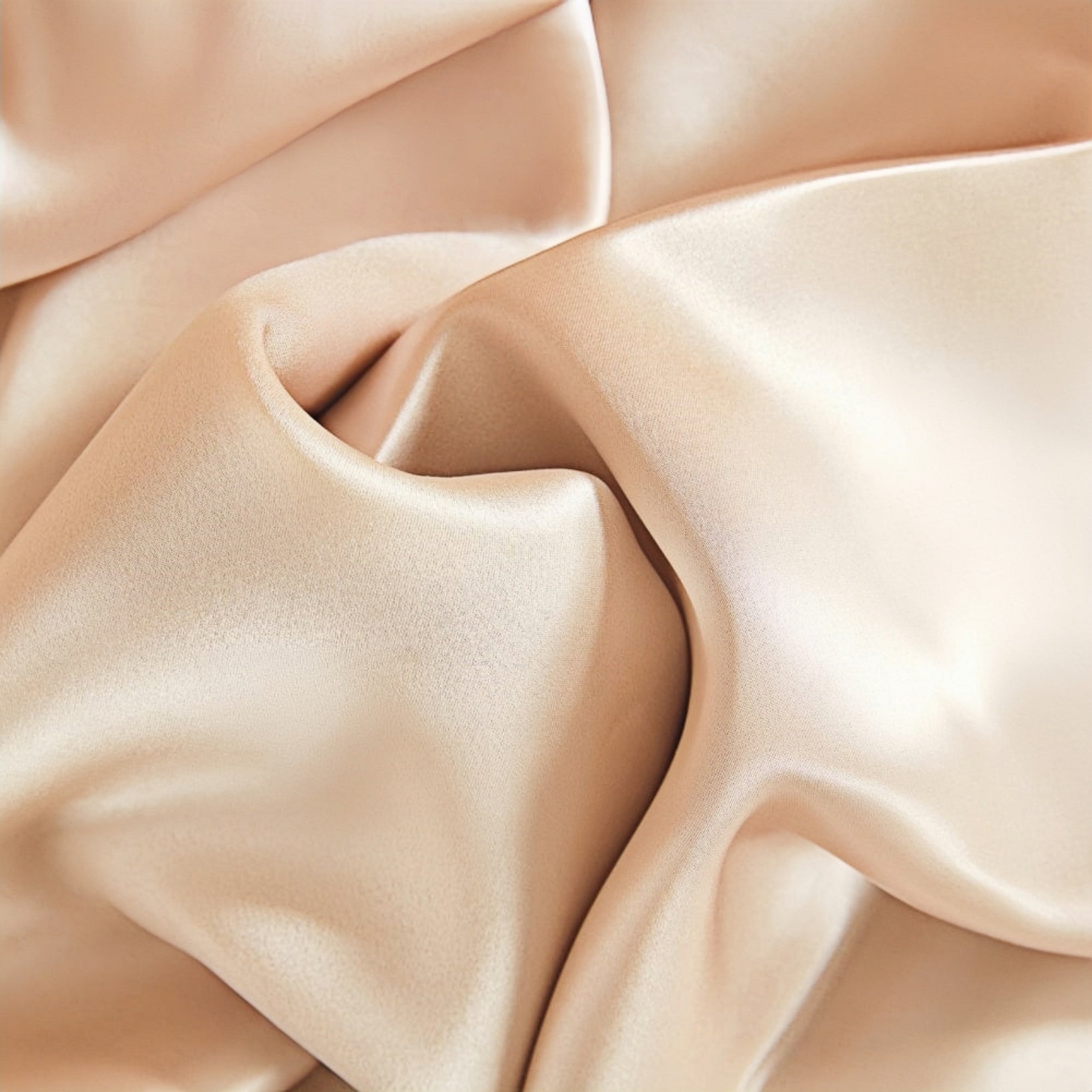 A close-up of smooth, beige satin fabric draped in soft folds.