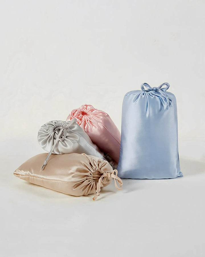 Four 16 Momme Antibacterial Mulberry Silk Travel Sleep Sacks from SusanSilk, in pastel colors (beige, silver, pink, and blue), are arranged against a plain white background.