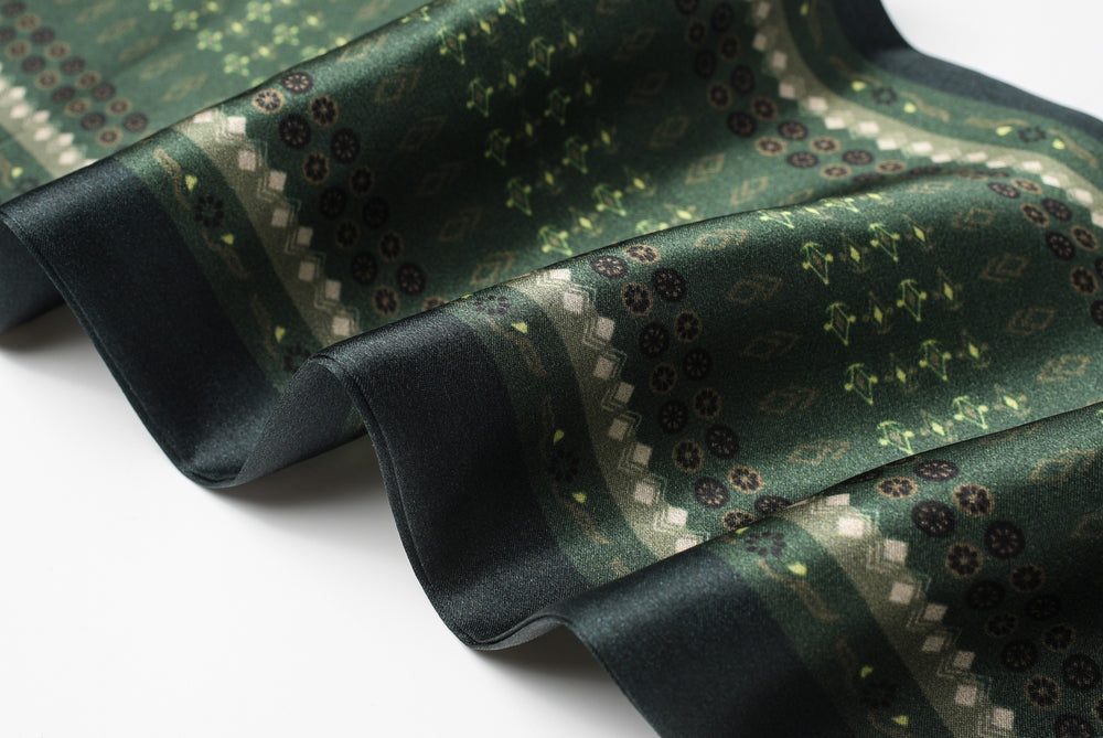 A close-up of the Dark Green Daisy Silk Long Fluttering Belt by SusanSilk, featuring a green, white, and dark teal geometric and floral pattern, showcasing its texture and design details.