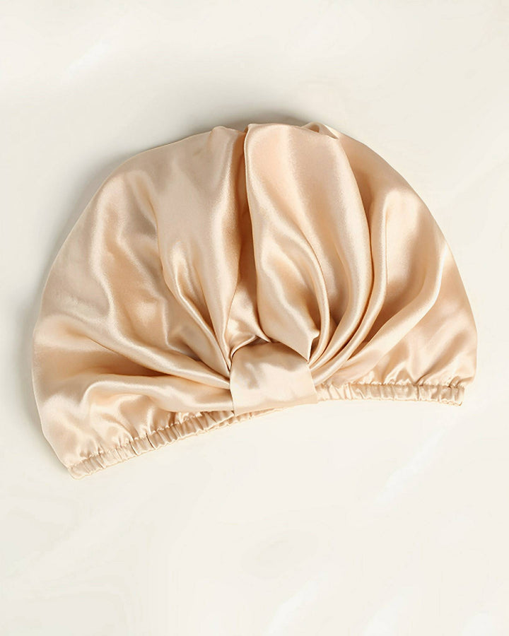 The Elegant Pleated Silk Bonnet For Sleeping by SusanSilk features a gathered, twisted front design and an elasticated band at the opening.