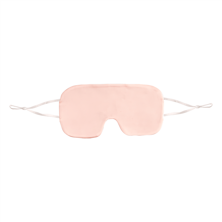 SusanSilk's Oversized Silk Eye Mask is a light pink silk sleep mask with white elastic straps, designed to cover the eyes for better sleep.