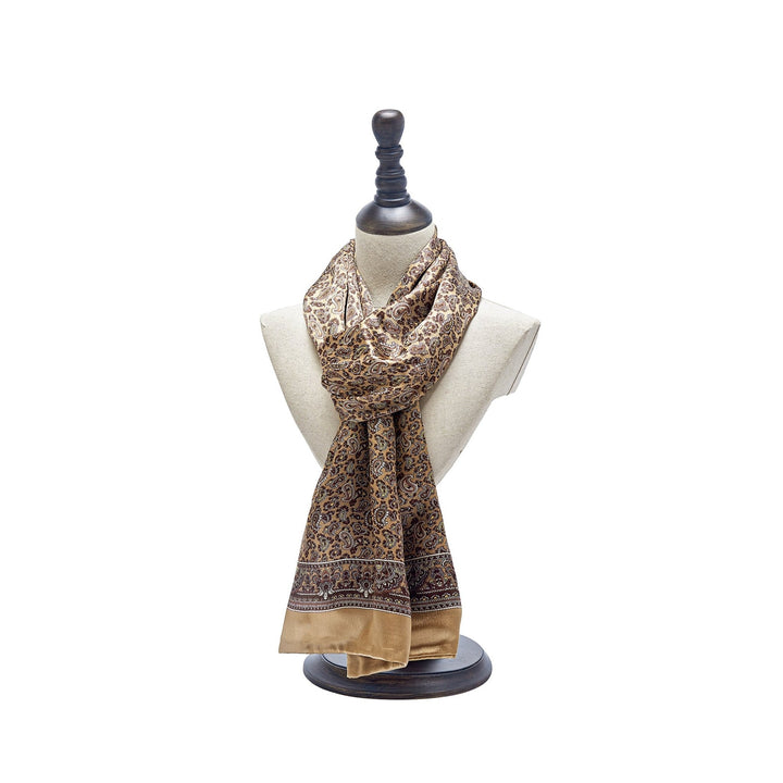 A Paisley Series Long Silk Scarf by SusanSilk, featuring a beige and brown pattern, is displayed on a white mannequin bust with a wooden base and top knob.