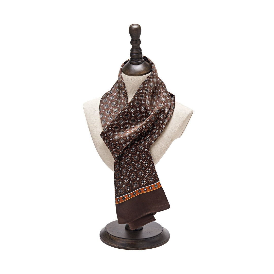 The Journey Grid Series Long Silk Scarf by SusanSilk, featuring a brown pattern, is elegantly displayed on a dress form mannequin with a dark wooden base.