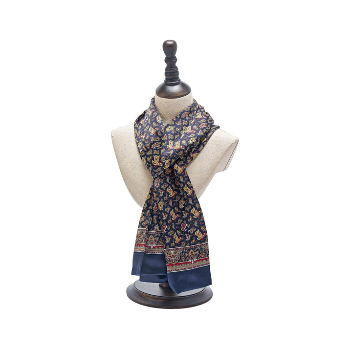 A decorative mannequin showcases a Paisley Series Long Silk Scarf from SusanSilk, featuring a navy blue pattern with tassels on the ends and crafted from luxurious silk.