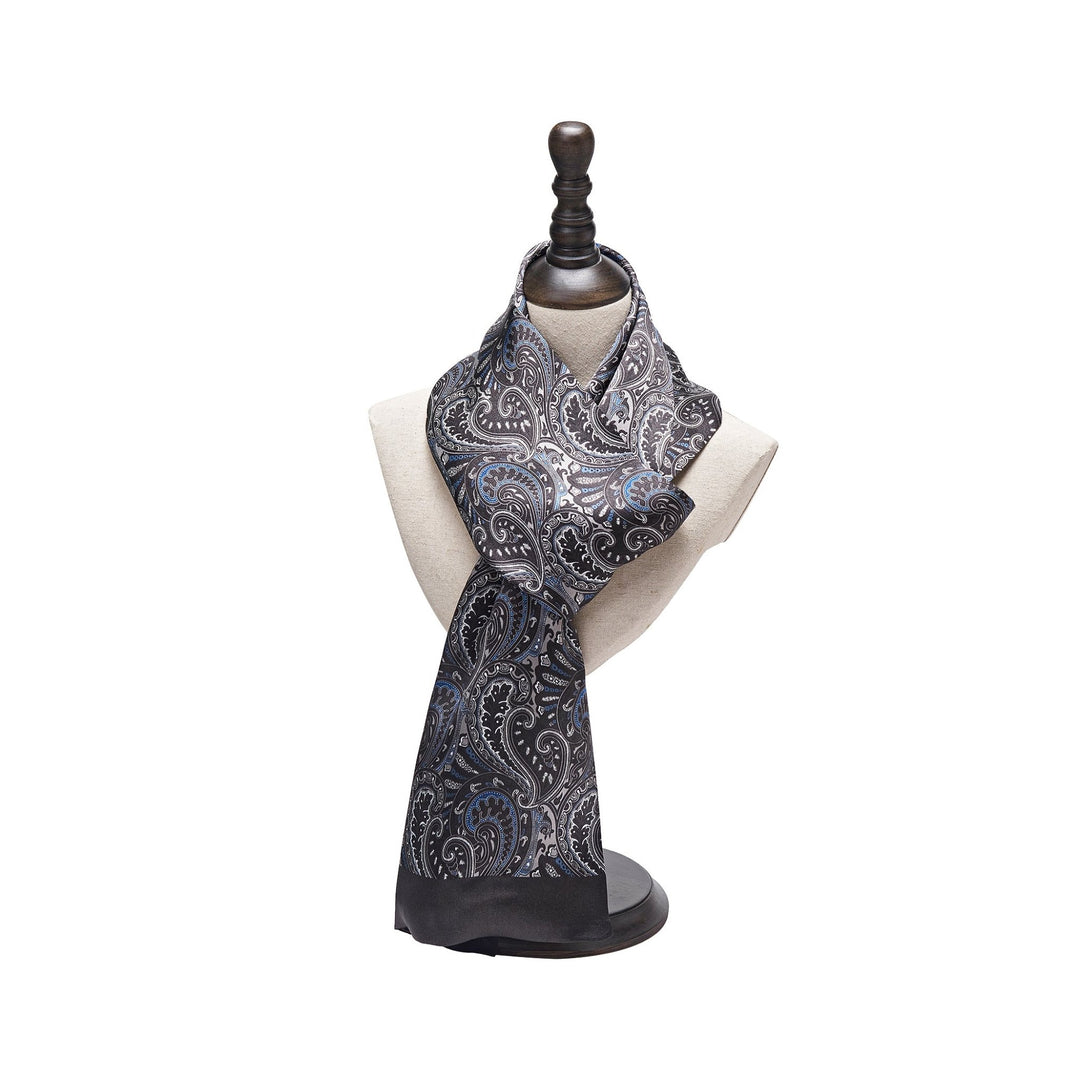 The Paisley Series Long Silk Scarf by SusanSilk, a black and white silk scarf with a paisley pattern, displayed on a light-colored torso mannequin stand with a dark wooden top.