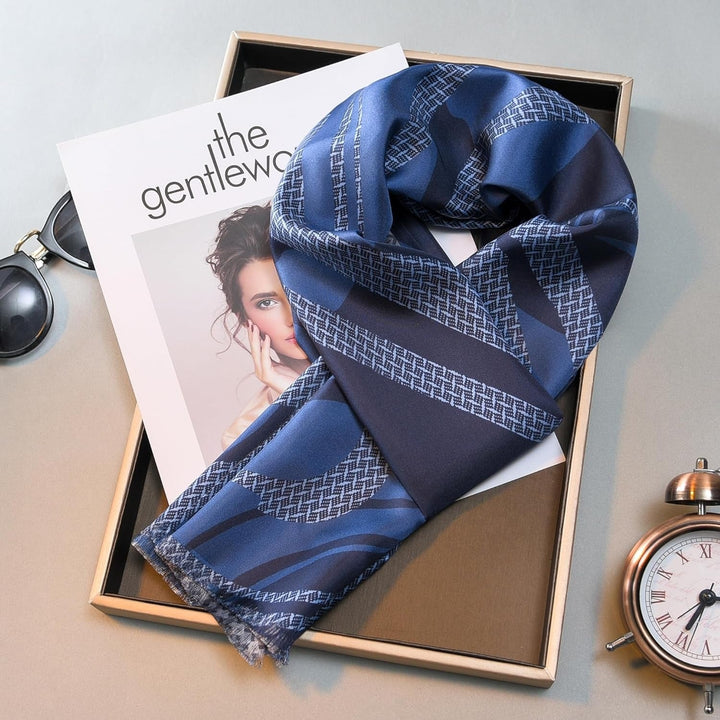 A Luxurious Men's Silk Twill Scarf in Dreamy Blue by SusanSilk is neatly laid over a magazine labeled "the gentlewoman," next to sunglasses and a clock.