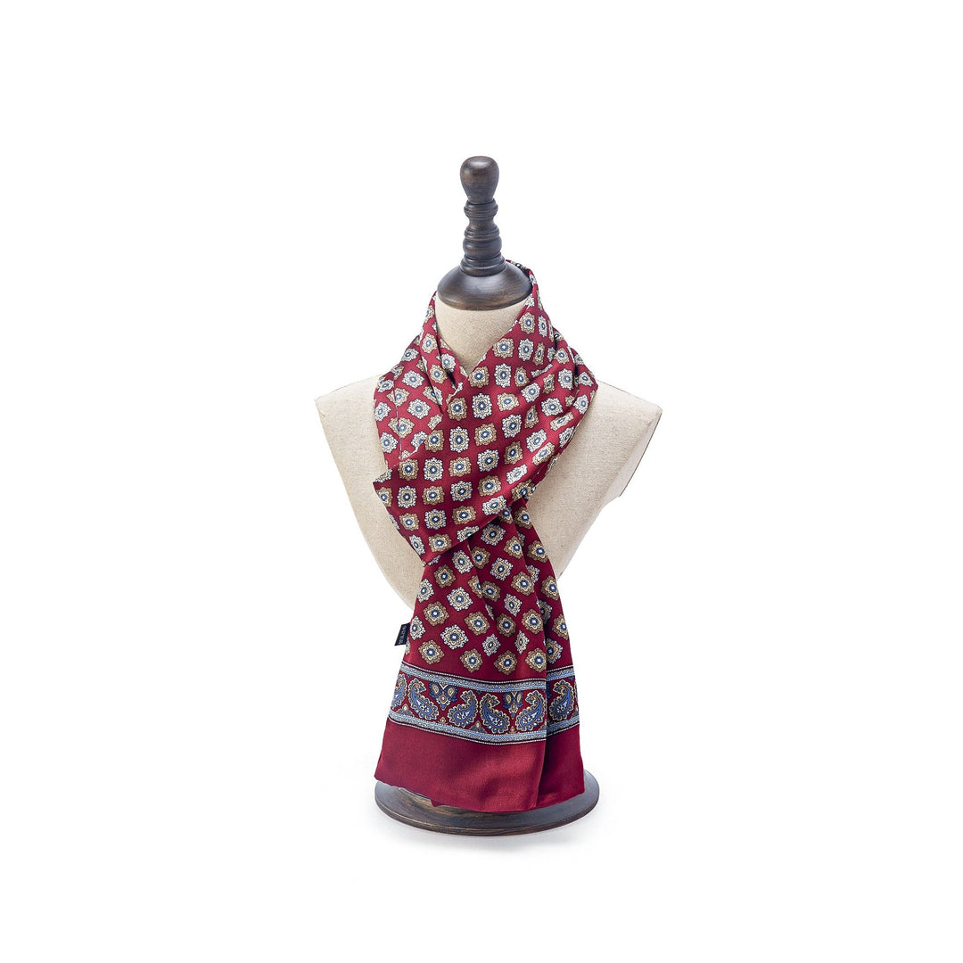 The Geometric Pattern Long Silk Scarf from SusanSilk, featuring intricate designs in blue and white, is displayed on a torso mannequin with a black stand.