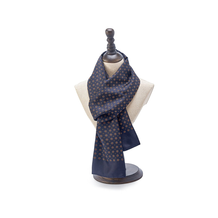 A SusanSilk Geometric Pattern Long Silk Scarf in navy is draped on a beige mannequin bust, set on a dark wooden stand.