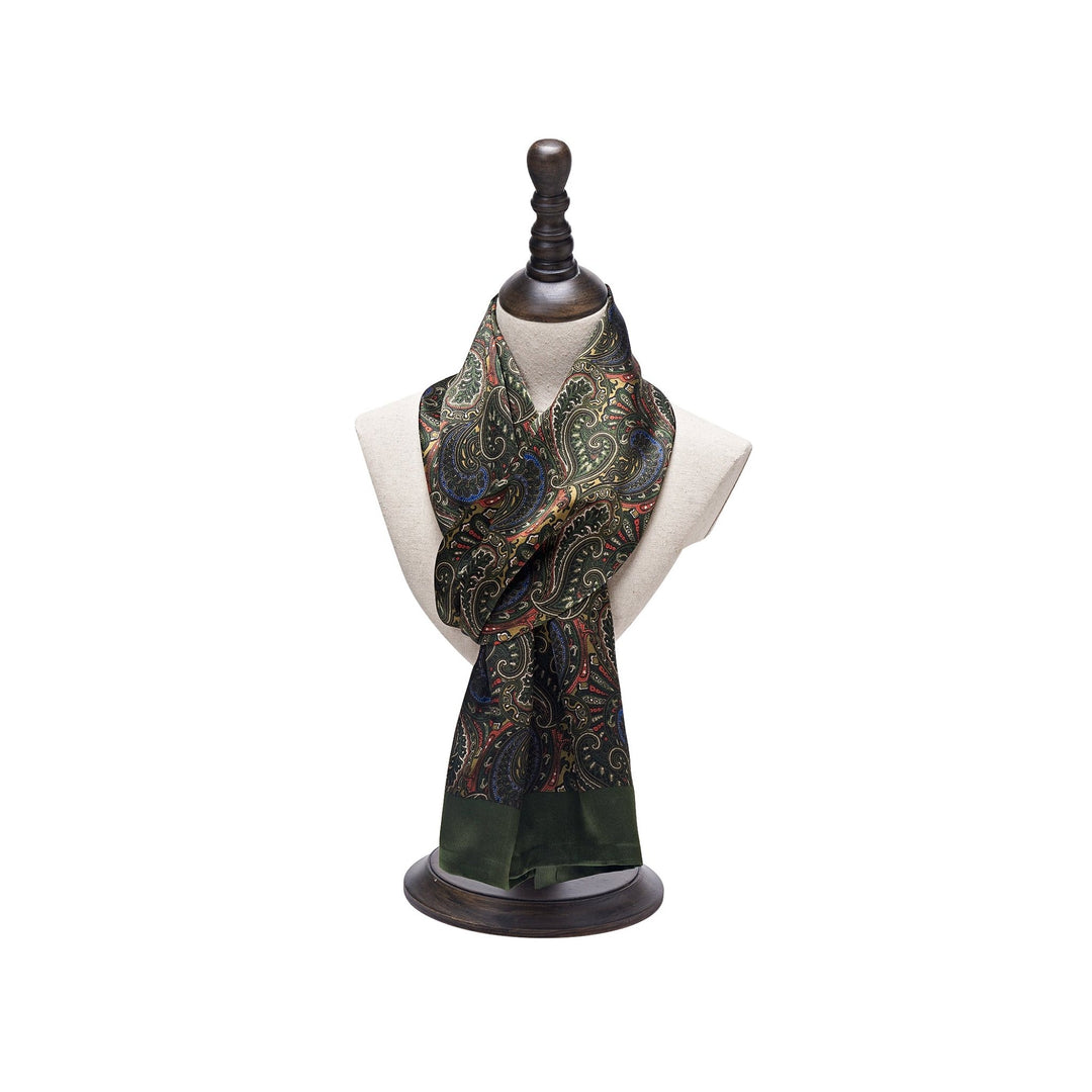 A dark green Paisley Series Long Silk Scarf by SusanSilk is displayed on a mannequin bust. The intricate paisley patterns are beautifully woven, while the base of the scarf features a plain green section.