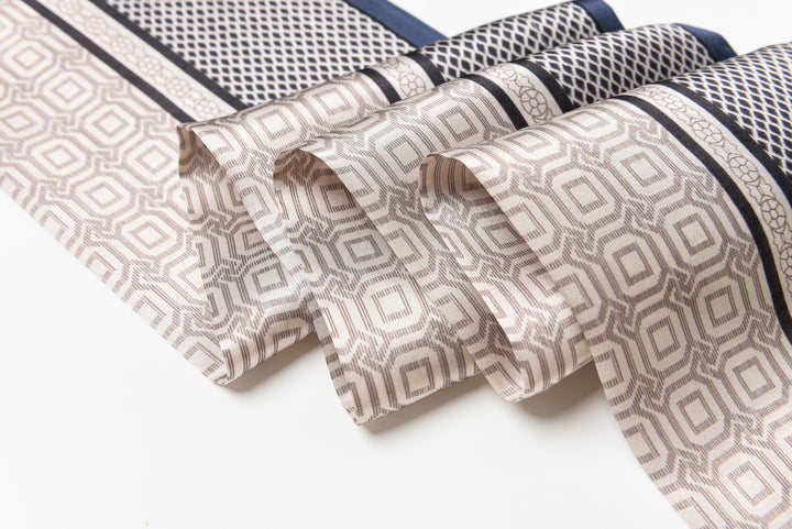 Close-up of a neatly folded Korean Style Silk Long Fluttering Belt by SusanSilk, featuring geometric designs in shades of beige, brown, and black on a white surface.