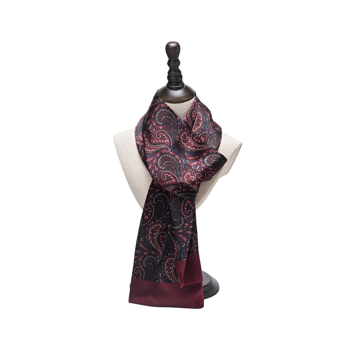 A black mannequin bust elegantly displays the luxurious SusanSilk Paisley Series Long Silk Scarf, featuring a sophisticated burgundy and black paisley pattern with red and tan accents.