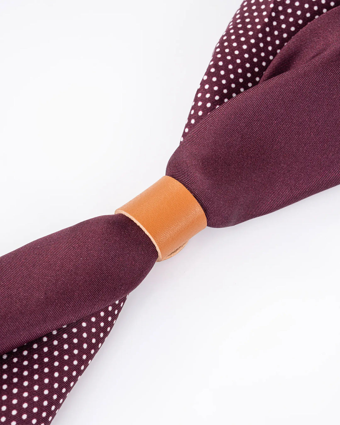 Close-up of a Straits Red Square Silk Scarf by SusanSilk, featuring a vibrant red hue with white polka dots and a brown leather knot holder, set against a pristine white background.