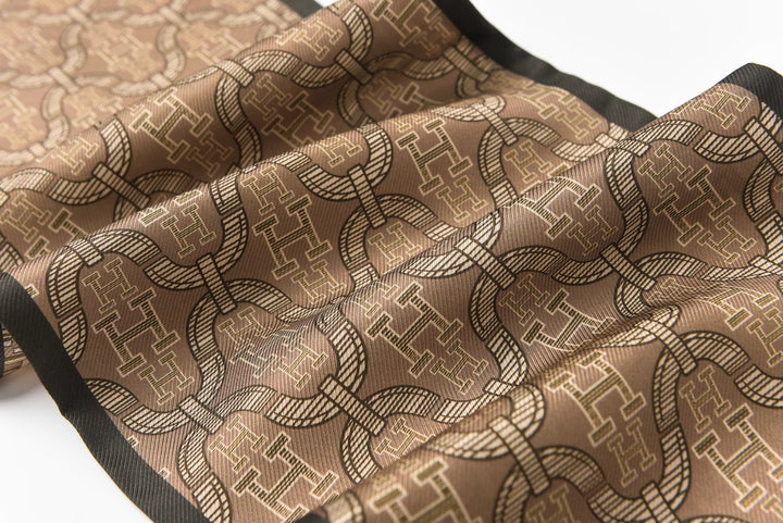 A close-up image showcasing the 16 Momme Affordable Luxury Silk Twill Long Silk Scarf-Classic H Style by SusanSilk, featuring a detailed, repeating geometric pattern on rich brown silk twill fabric with elegant black edges.