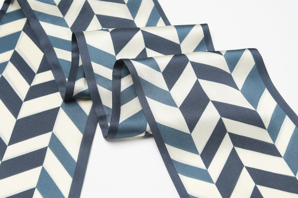 A luxurious Blue Staircase Silk Long Fluttering Belt from SusanSilk, featuring a geometric herringbone pattern in shades of blue and white, laid out on a flat surface.