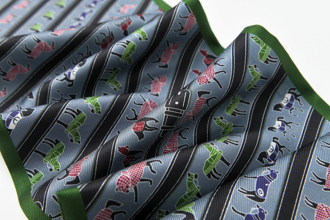 A close-up of the 16 Momme Affordable Luxury Silk Twill Long Silk Scarf-Green Pony by SusanSilk, featuring a pattern of small colorful cars on gray and black stripes, accented with a green trim.