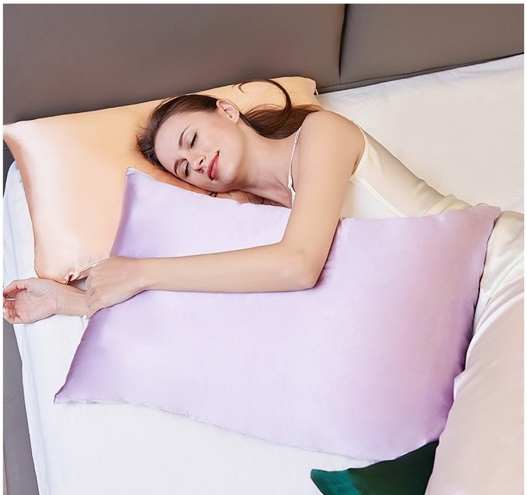 A woman sleeps on a bed, hugging a purple pillow with her head resting on a peach-colored SusanSilk 19 Momme Silk Pillowcase Zipper.