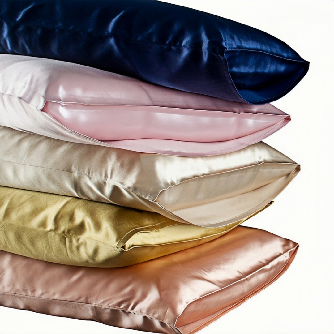 A stack of SusanSilk's 22 Momme High Gloss Silk Pillowcase Envelopes in various colors—blue, pink, beige, gold, and peach—arranged in a horizontal pile against a white background.