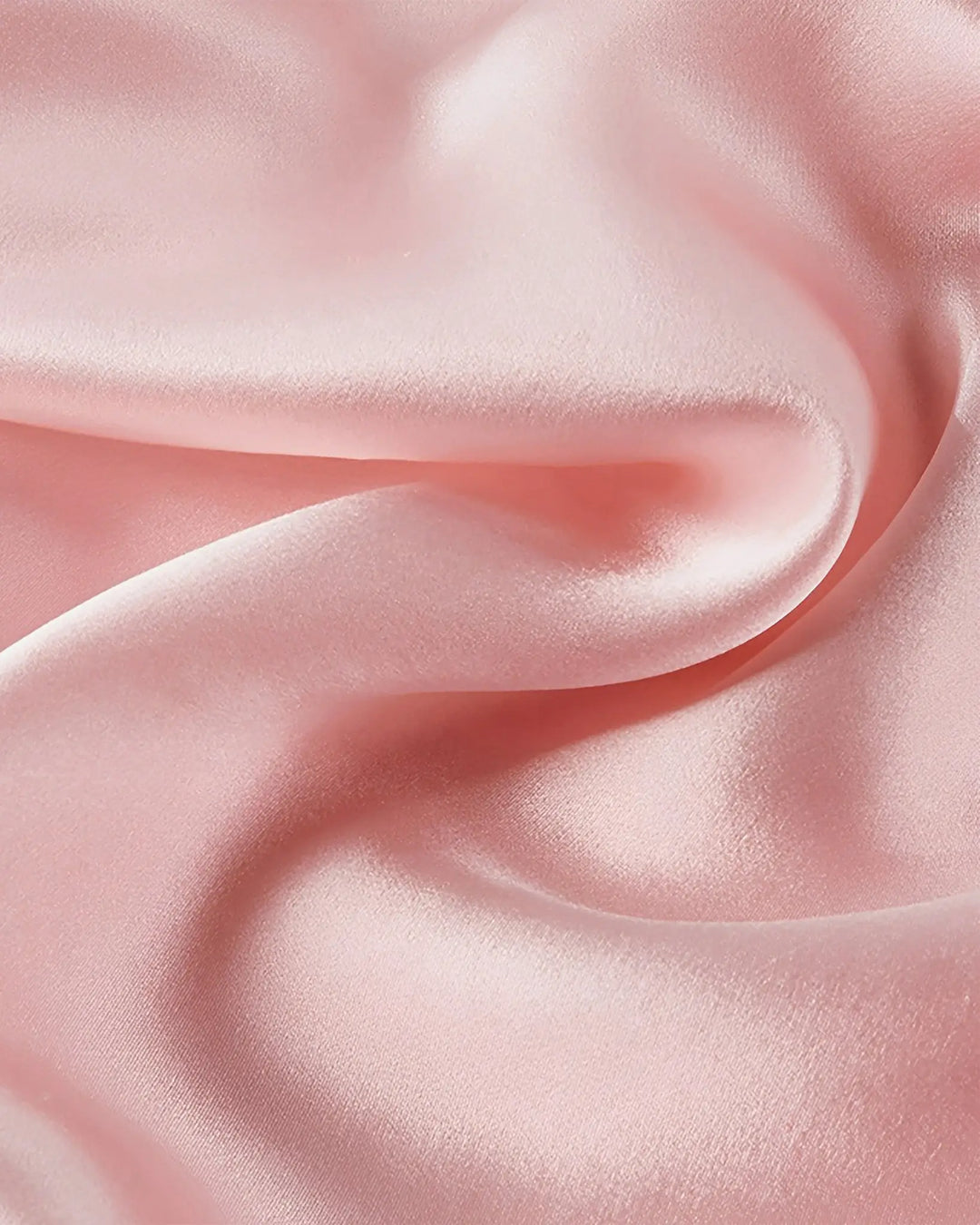 A close-up view of SusanSilk's 16 Momme Antibacterial Mulberry Silk Travel Sleeping Bag, showcasing its smooth, light pink silk satin fabric with gentle folds and a glossy finish.