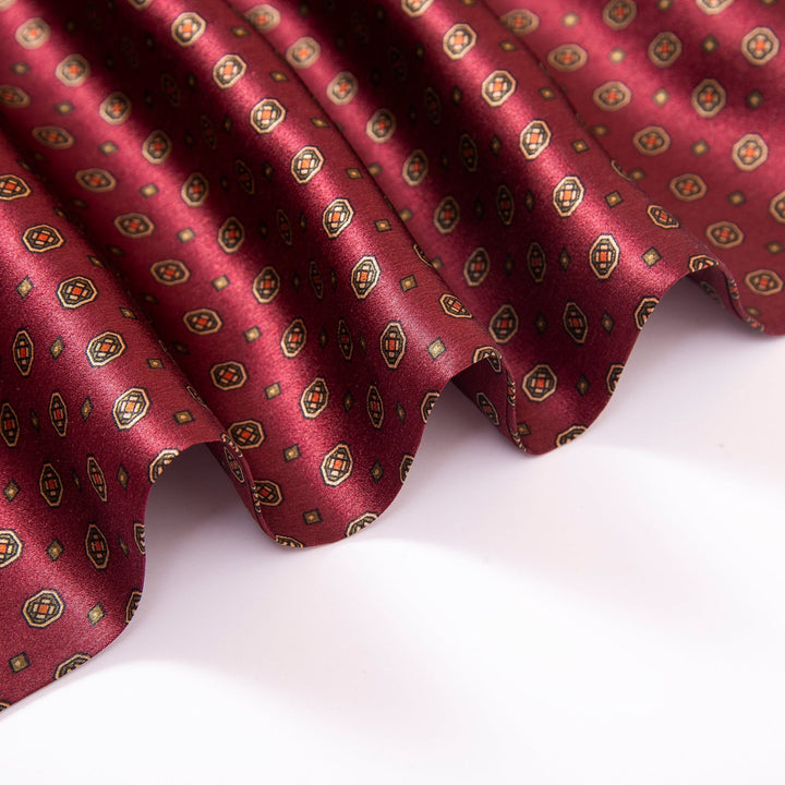 Close-up of a SusanSilk Geometric Pattern Long Silk Scarf in maroon, draped in gentle waves.