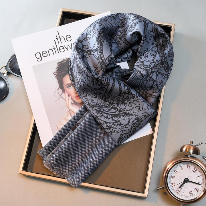 A SusanSilk Luxurious Men's Silk Twill Scarf in Gentleman Gray is displayed on a magazine titled "The Gentlewoman," placed in a tray alongside sunglasses and a silver pocket watch on a light background.