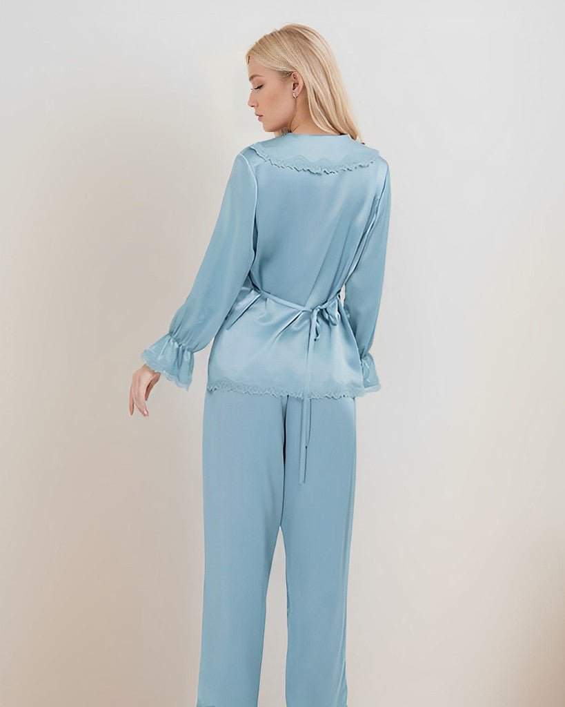 A person with long blonde hair is standing, turned away from the camera, and wearing a light blue 22 Momme Lace Silk Pajamas Set by SusanSilk.