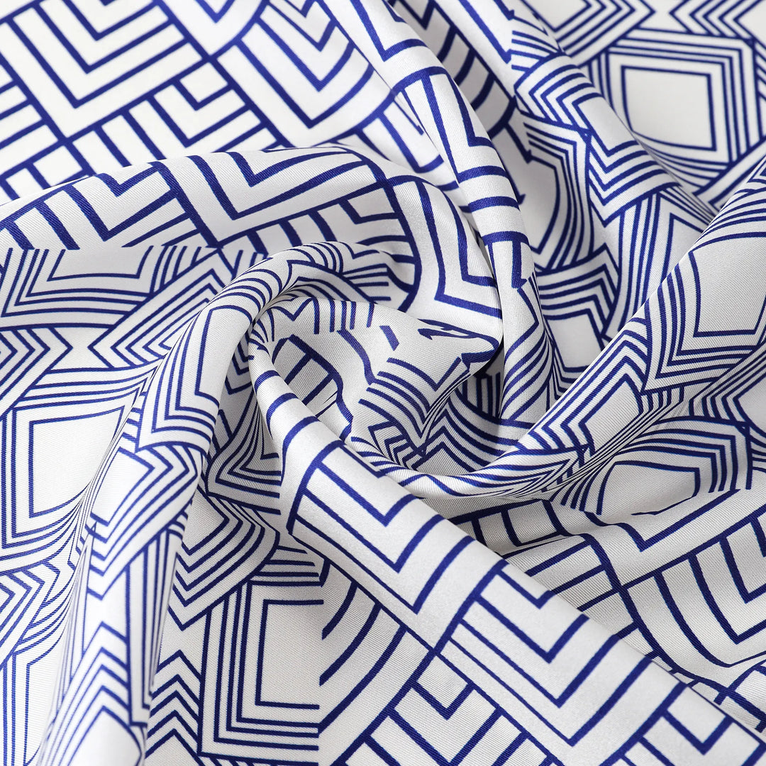 Close-up of the SusanSilk Land Off Blue Square Silk Scarf, showcasing a geometric pattern with blue and white intersecting lines.