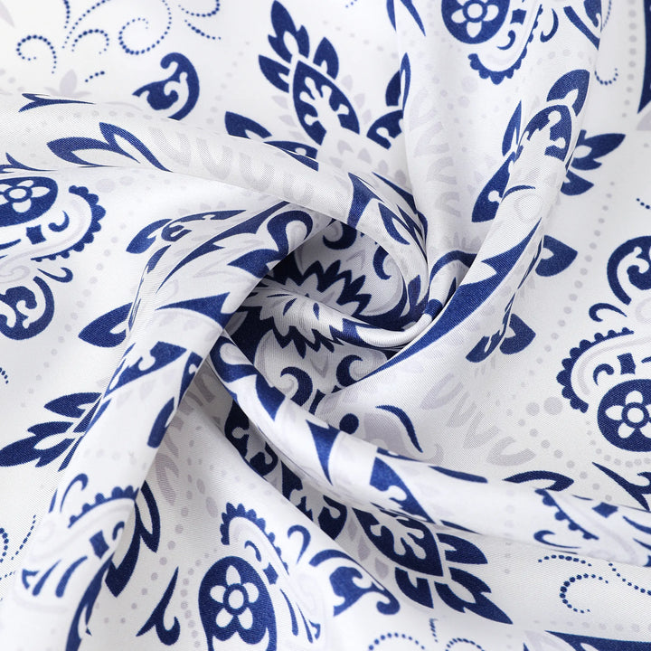 Close-up of the Cashew Orchid Flower Square Silk Scarf by SusanSilk, featuring a white silk fabric adorned with a blue floral and paisley pattern, shown in a twisted formation.