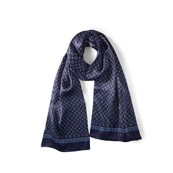 The SusanSilk Journey Grid Series Long Silk Scarf in dark blue, featuring a geometric pattern with small squares and dots, is laid flat with a loose loop at the top.