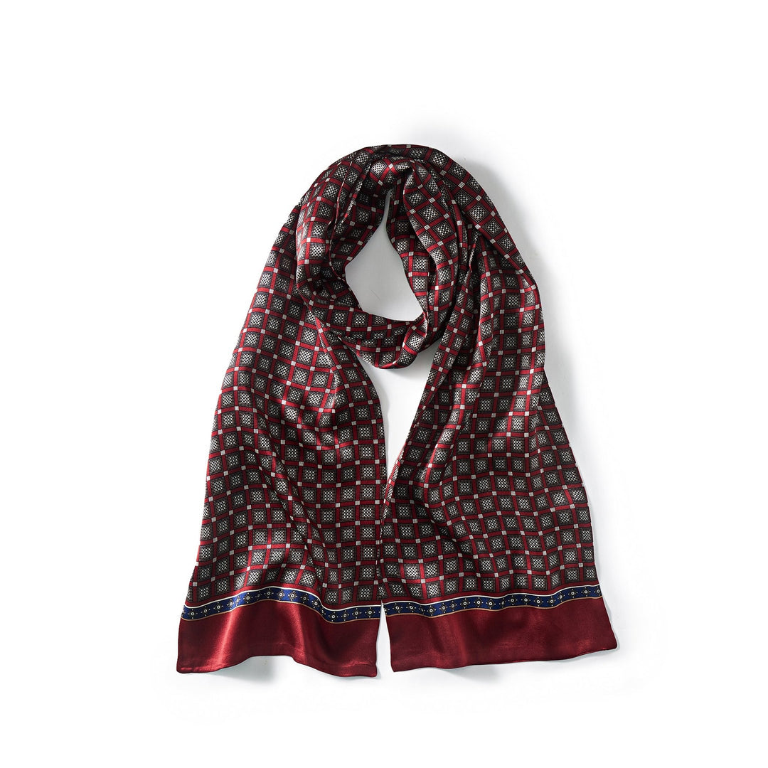 A Journey Grid Series Long Silk Scarf from SusanSilk, featuring a small, intricate geometric pattern in red and black, lies draped on a white surface.