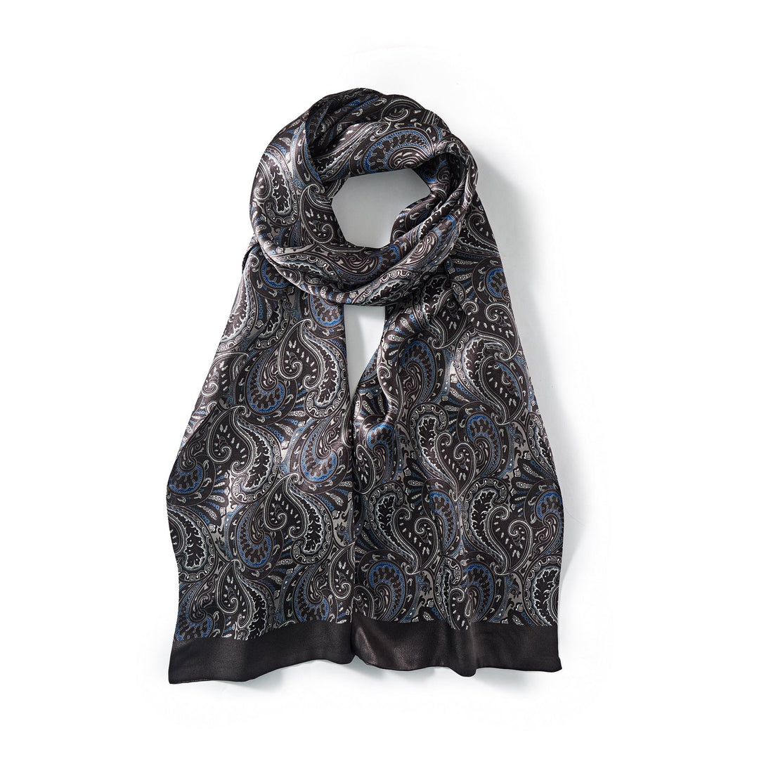 A Paisley Series Long Silk Scarf by SusanSilk, showcasing a classic black background adorned with blue and white paisley patterns, elegantly draped in a looped arrangement against a white backdrop.