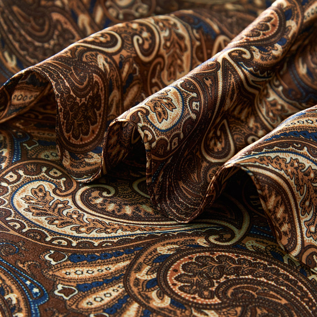 Close-up of the Paisley Series Long Silk Scarf by SusanSilk, showcasing its intricate paisley pattern in brown, blue, and beige hues with visible folds and texture. The luxurious silk material accentuates the elegance of SusanSilk craftsmanship.