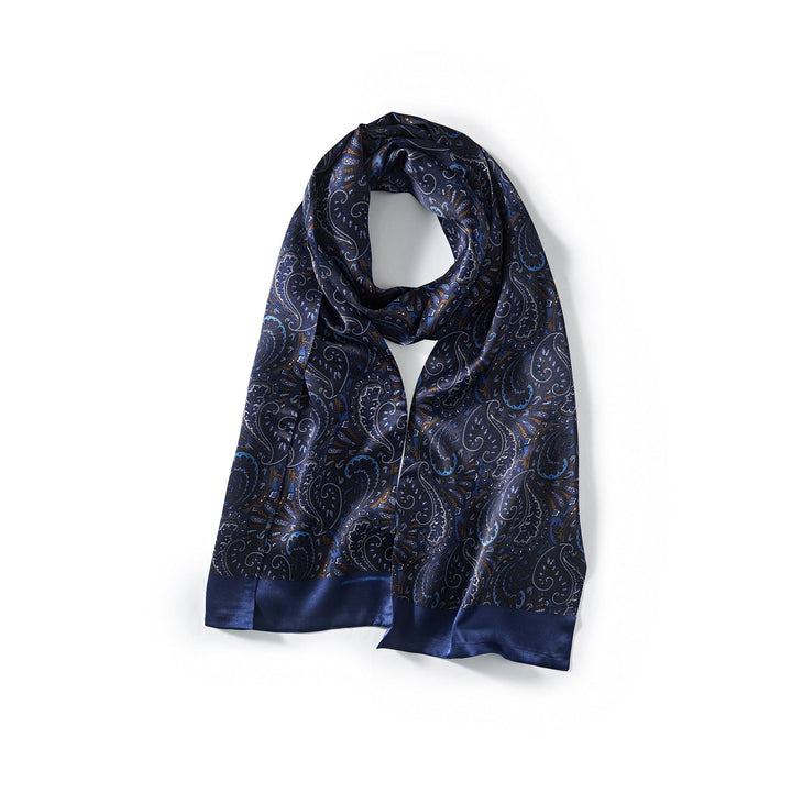 A SusanSilk Paisley Series Long Silk Scarf, featuring a navy blue base with a paisley pattern and shiny satin borders, arranged in a loose loop against a white background.