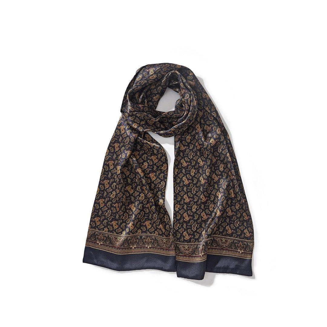 The Paisley Series Long Silk Scarf by SusanSilk features an intricate paisley pattern in gold and brown tones on a dark blue silk background.