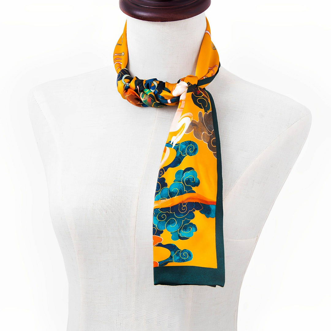 A SusanSilk mannequin displays a vibrant Fairy Deer Long Mulberry Silk Scarf with an orange, green, and blue pattern featuring floral and swirling designs.