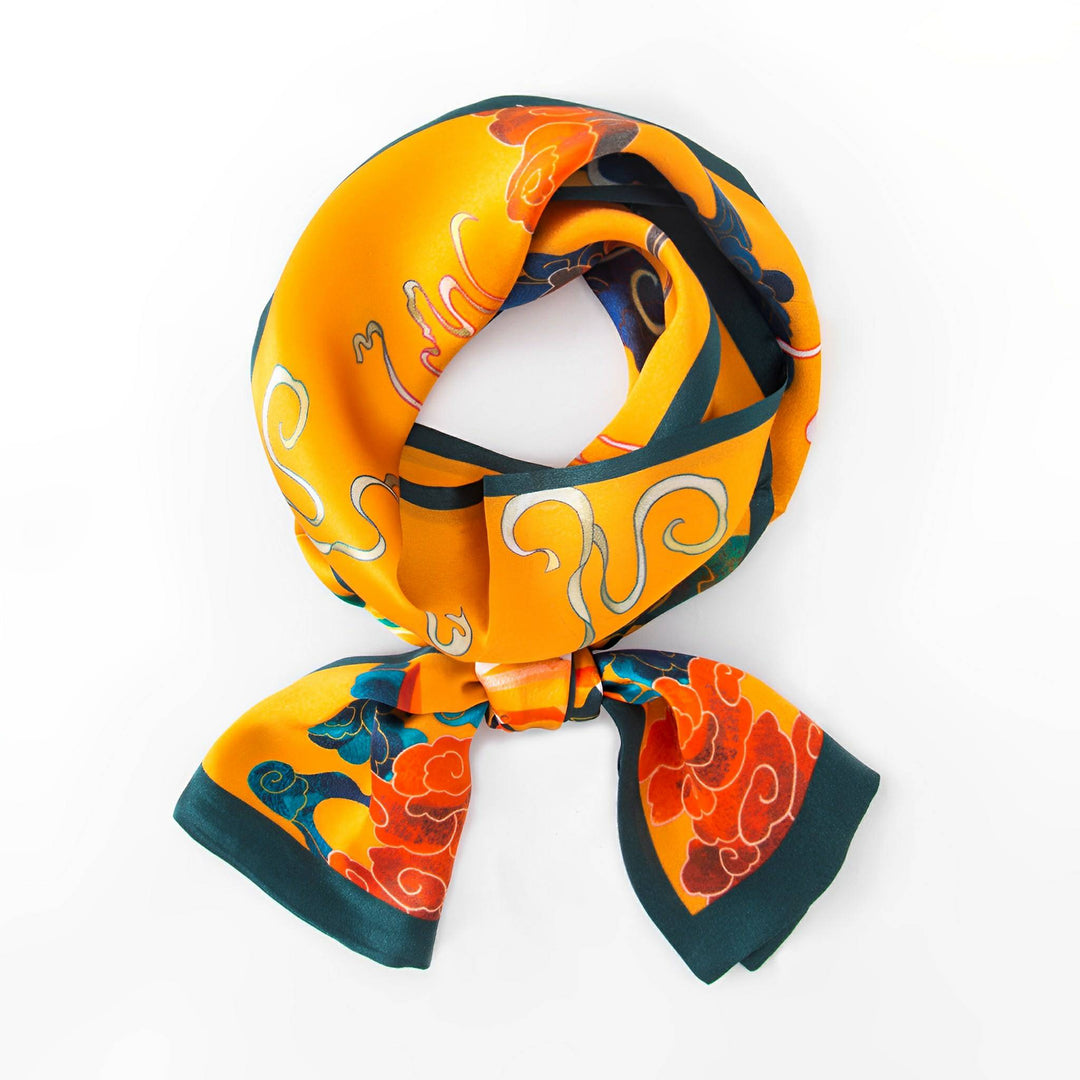 A vividly colored Fairy Deer Long Mulberry Silk Scarf by SusanSilk, showcasing abstract patterns of orange, red, and teal, intricately folded and tied into a loose knot against a white background.