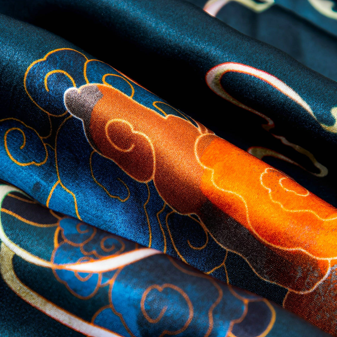 Close-up of the vibrant, folded Fairy Deer Long Mulberry Silk Scarf with an intricate orange and blue pattern from SusanSilk.