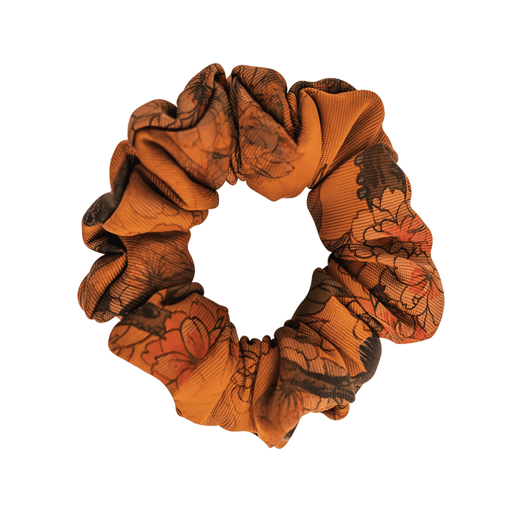 A Gambiered Canton Gauze Silk Scrunchie from SusanSilk, featuring dark, intricate floral patterns on a brown base, is displayed against a white background.