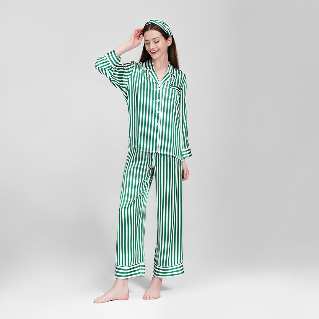 A person stands smiling in the 19 Momme Chic Stripe Silk Pajamas Set by SusanSilk, with one hand touching their head and the other relaxed by their side, against a plain background.