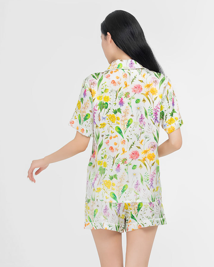 Person with long dark hair wearing a SusanSilk Floral Short Silk Pajamas Set, standing with their back turned, on a plain white background.