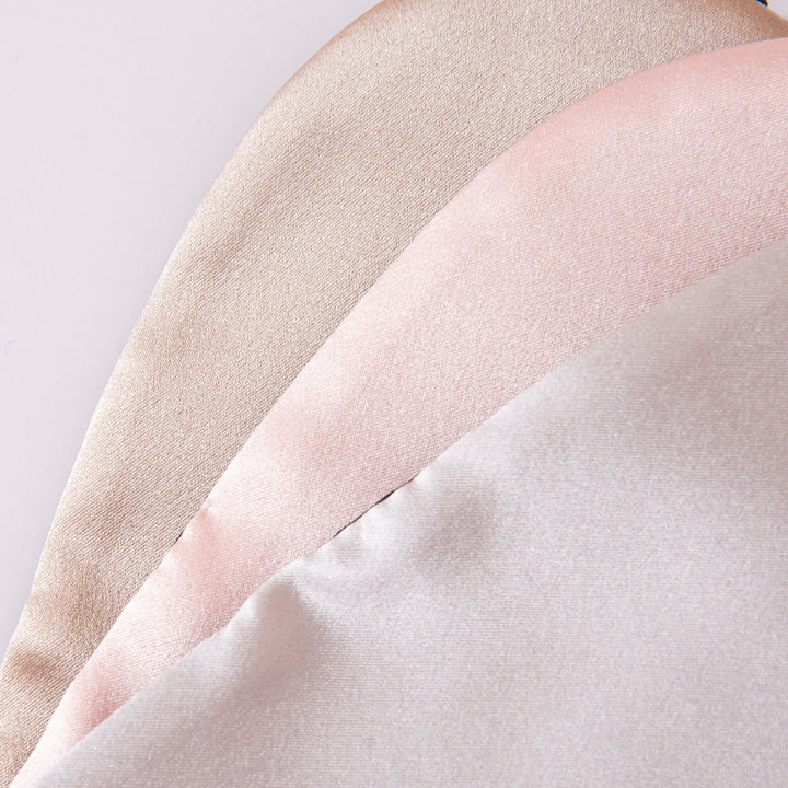 Close-up image of three Earth Tones Double Side Silk Eye Masks from SusanSilk in an overlapping arrangement, showcasing their sheen and texture. The masks are beige, pink, and off-white in color.