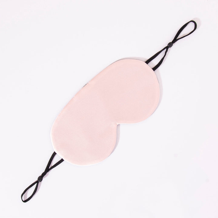 A light pink Earth Tones Double Side Silk Eye Mask by SusanSilk, featuring black adjustable straps, laid flat on a white surface.