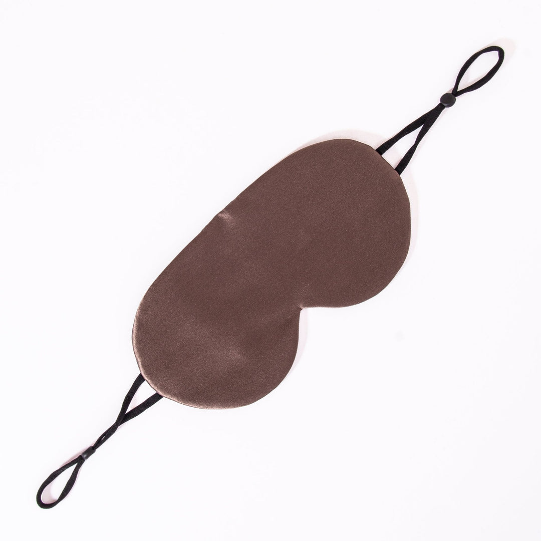 The Earth Tones Double Side Silk Eye Mask by SusanSilk, featuring a brown design with black elastic straps, is laid flat against a white background.