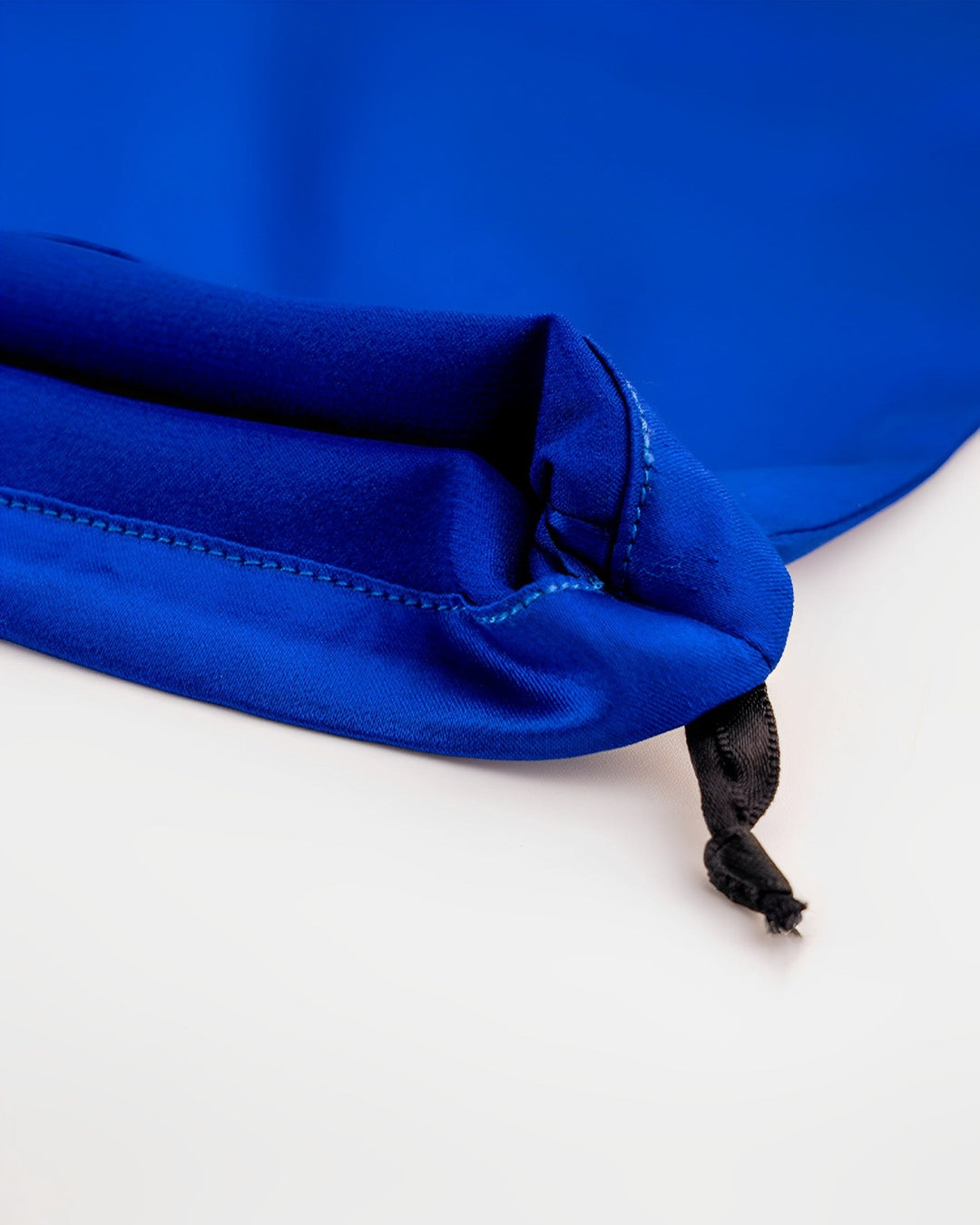 Close-up of the corner of a blue silk drawstring bag from the 19 Momme Silk U-Shaped Pillow Travel Set by SusanSilk, highlighting the black drawstring and folded fabric detail against a white background.