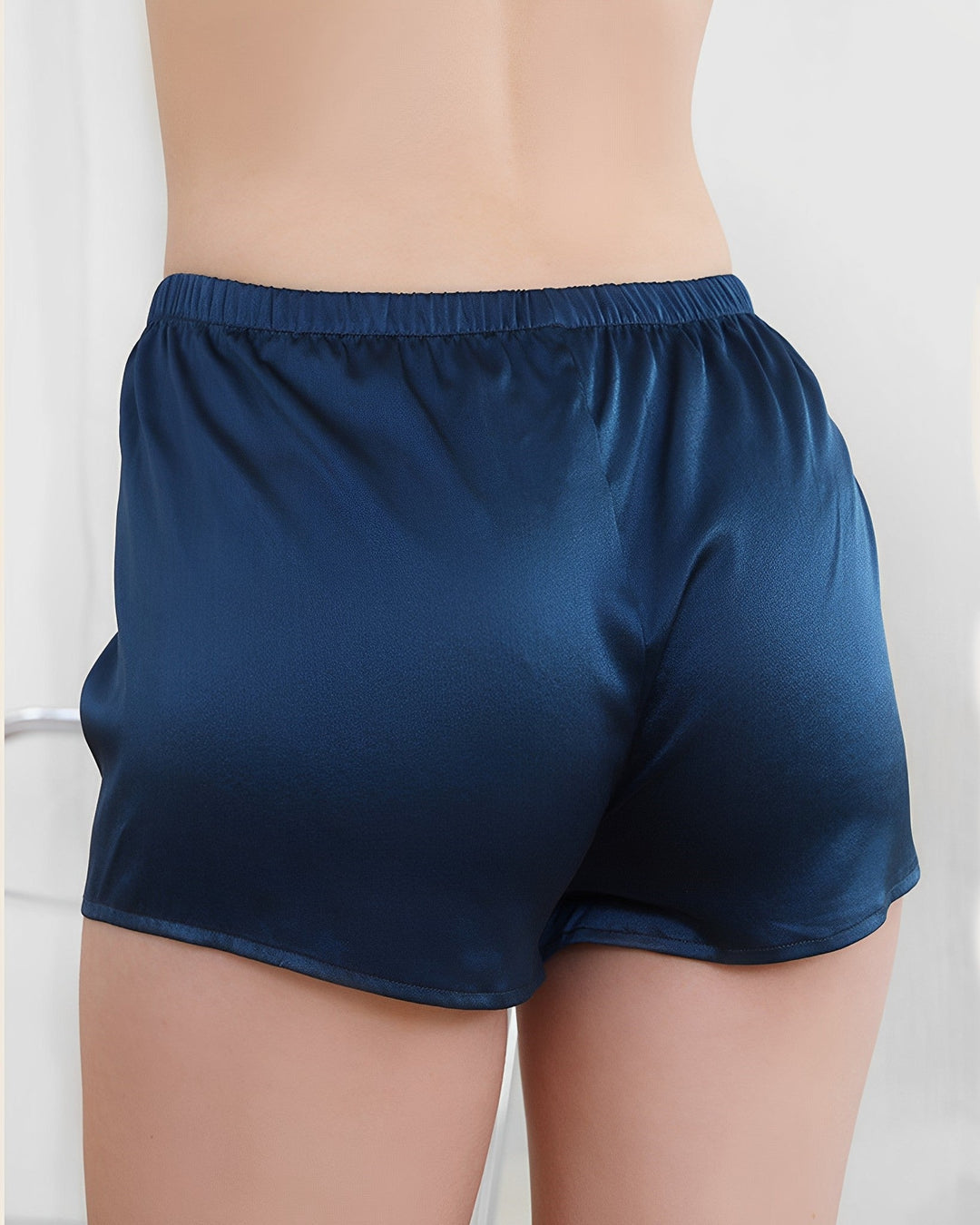 Close-up of a person’s lower back and legs wearing SusanSilk 19 Momme Silk Underwear Boxers in shiny blue.