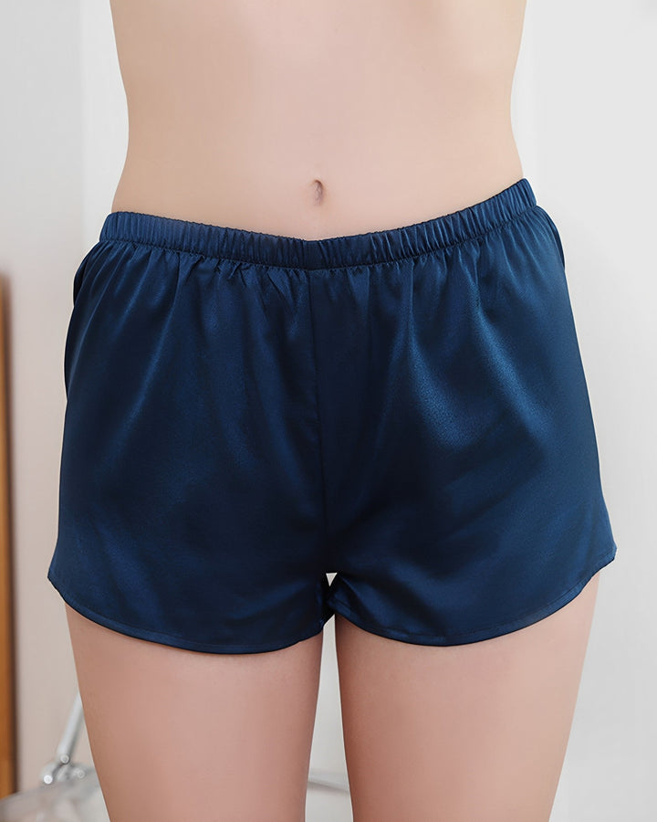 A person wearing SusanSilk's 19 Momme Silk Underwear Boxers in navy blue satin stands with their torso visible from the waist down.