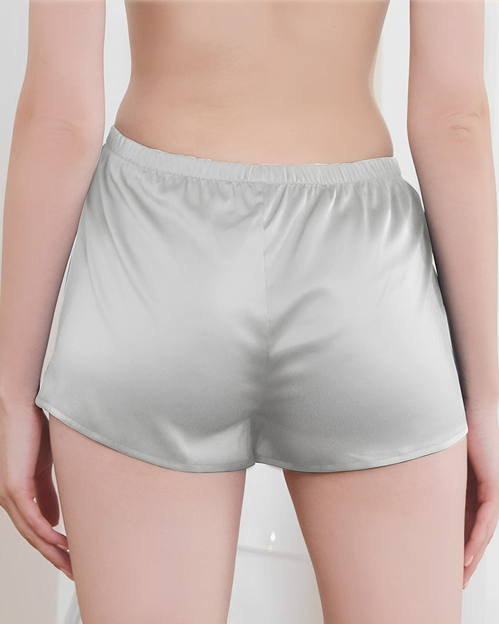 A person's lower back and buttocks wearing SusanSilk 19 Momme Silk Underwear Boxers, viewed from behind, the fabric shimmering like silk under the soft light.