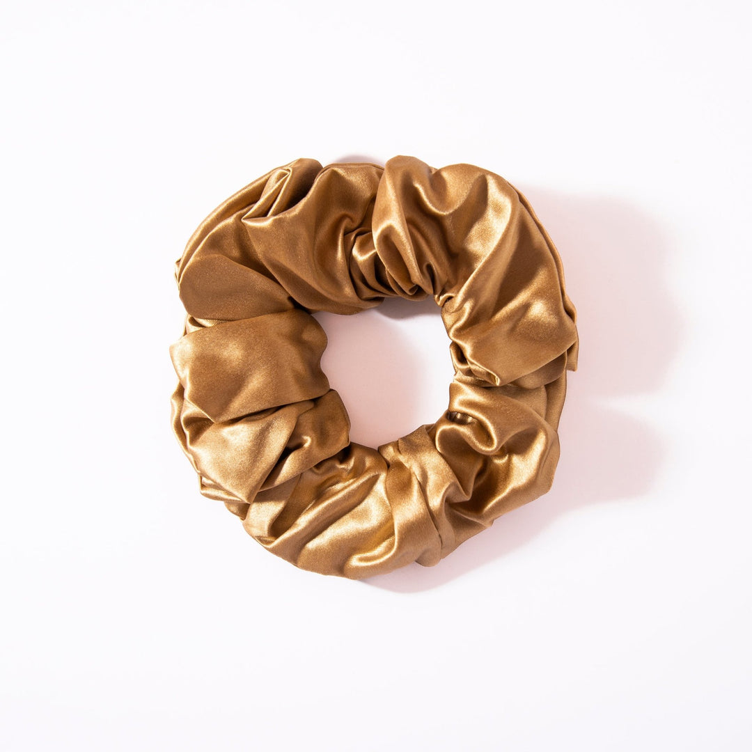 A gold satin scrunchie from the 22 Momme Luxury Silk Scrunchies Set 4-Pack by SusanSilk is elegantly placed on a white background.