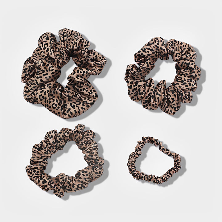 The 22 Momme Luxury Silk Scrunchies Set 4-Pack by SusanSilk includes four leopard print hair scrunchies of varying sizes, elegantly displayed on a plain background.