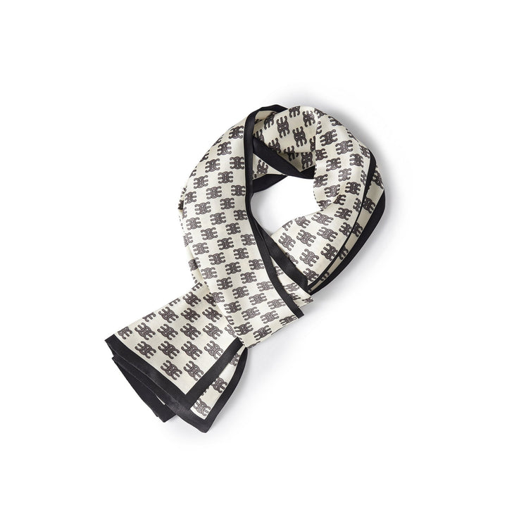 The Arc De Triomphe Narrow Long Silk Scarf by SusanSilk, featuring a repetitive black symbol pattern and black borders on white silk, folded neatly against a white backdrop.