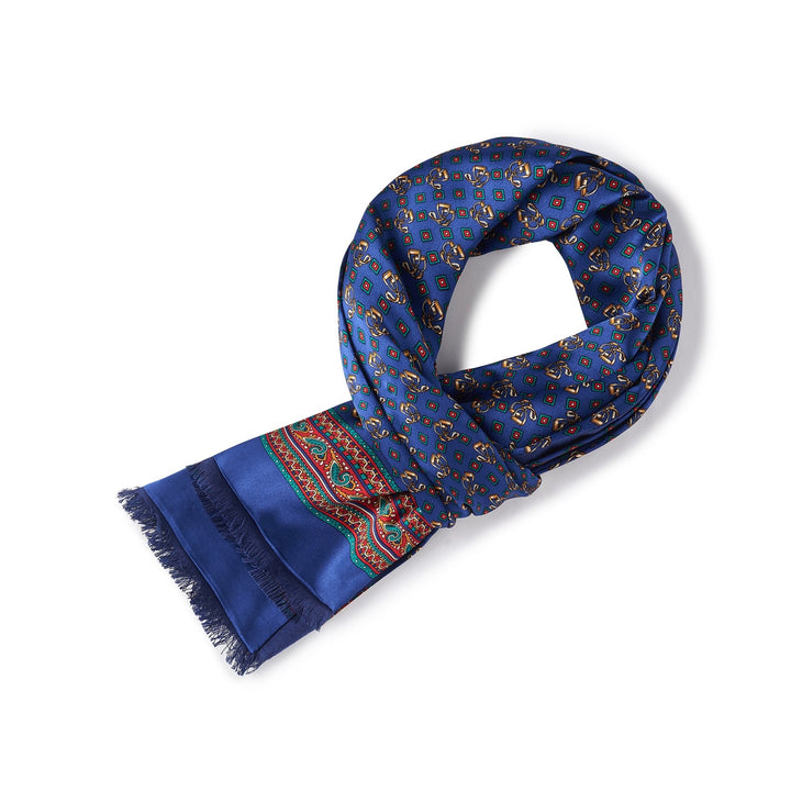 A blue Buckle Pattern Long Silk Brushed Scarf by SusanSilk, with a frayed end, featuring a pattern of yellow and red geometric shapes, and a green and red border design.